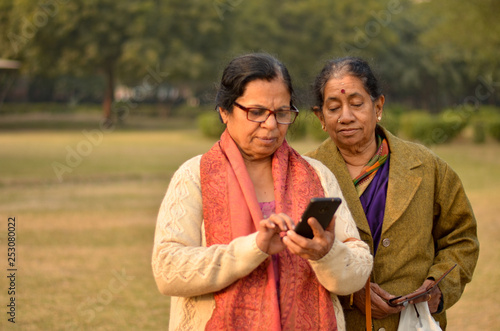 Wallpaper Mural Senior north Indian and south Indian women looking in a smartphone in a park in Delhi winters Torontodigital.ca
