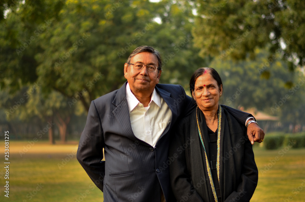 Portrait of a happy looking retired senior Indian man and woman couple smiling and posing in a park outdoor setting in Delhi, India. Concept love Portrait of a happy looking retired senior Indian man and woman couple smiling and posing in a park outdoor setting in Delhi, India. Concept love