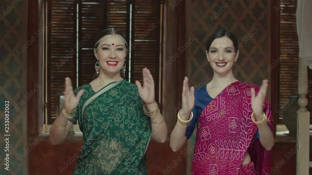 Cheerful females in colorful ethnic indian sari with bindi points on ...