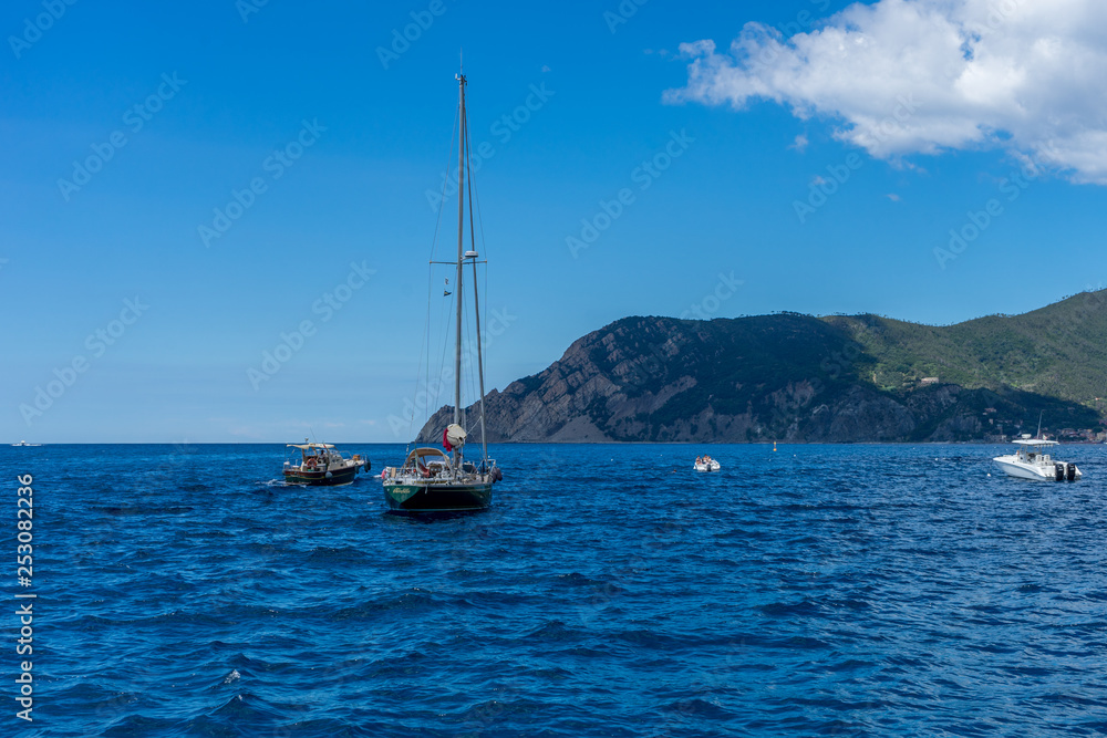 Italy, Cinque Terre, Monterosso, a blue and white boat sitting next to a body of water