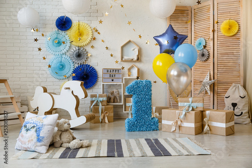 Photography Birthday gold and silver decorations with gifts, toys, garlands and figure for little baby party on a white bricks background
