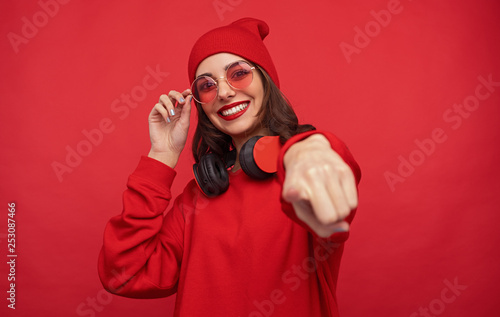 Trendy bright girl in red clothes pointing at camera 