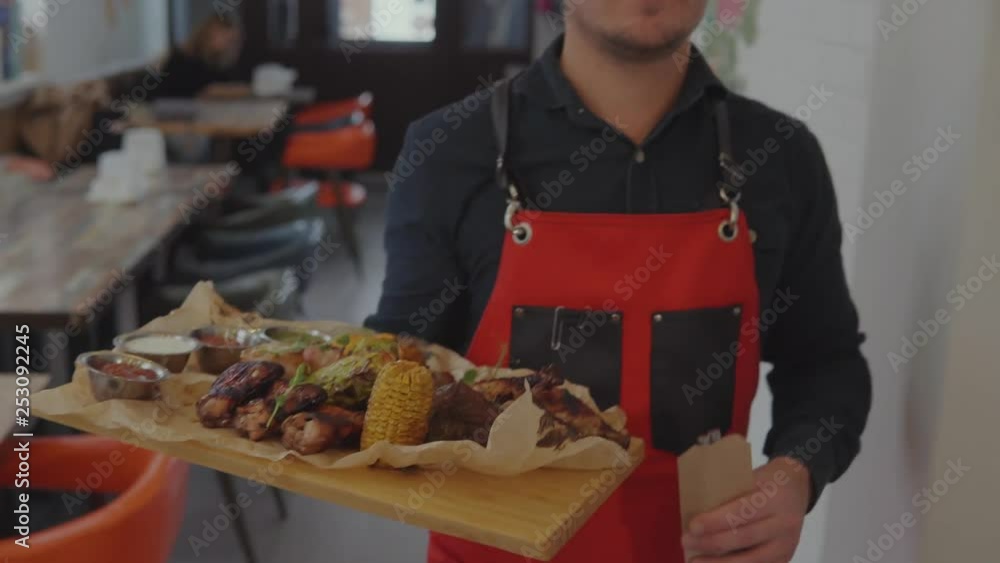 Waiter serving big plate with meat to client. Waiter serving big plate with meat to client.