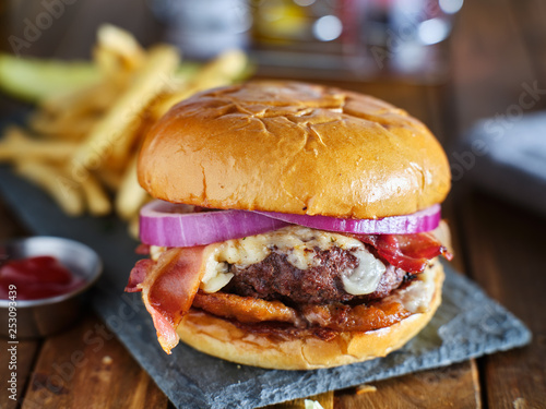 western style bacon burger with onion rings and bbq sauce close up