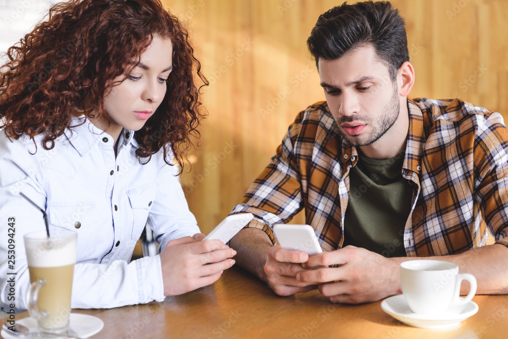 handsome man and beautiful woman using smartphone at cafe handsome man and beautiful woman using smartphone at cafe