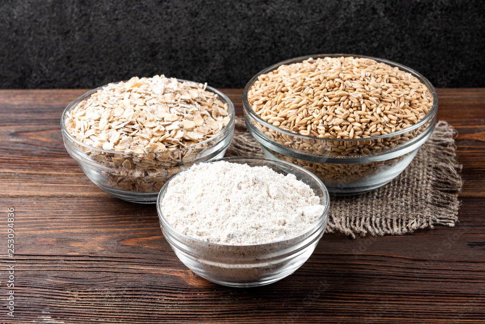 Rolled oats, oat and flour on dark wooden background. Rolled oats, oat and flour on dark wooden background.