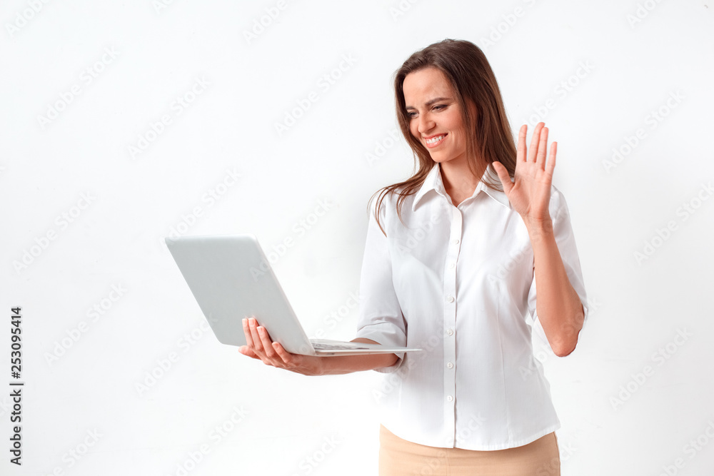 Online communication. Woman standing isolated on white having video call on laptop waving to camera cheerful Online communication. Woman standing isolated on white having video call on laptop waving to camera cheerful