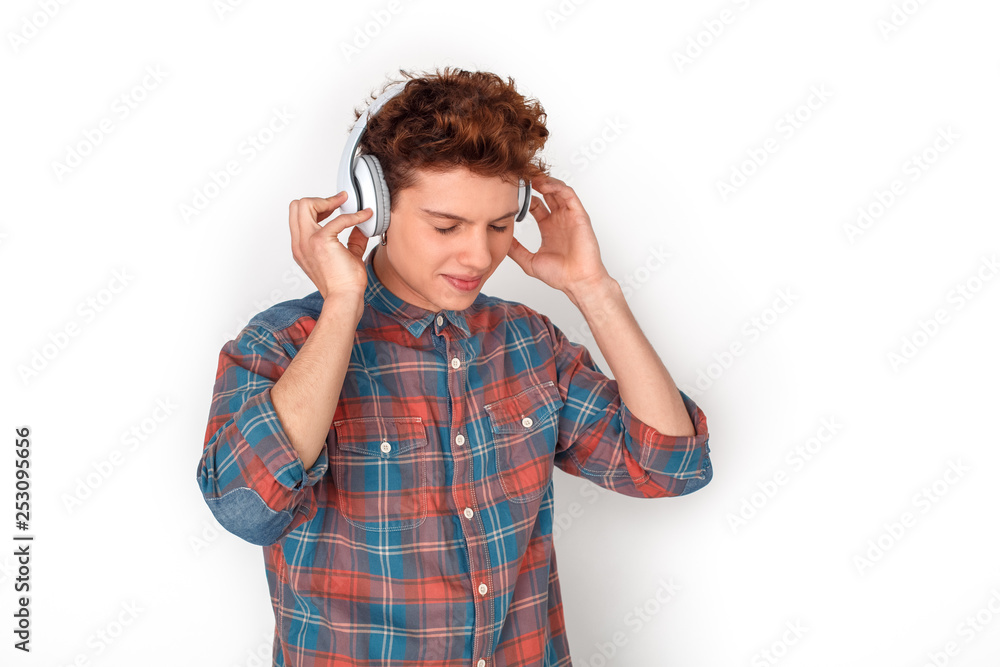 Teenager in headphones studio standing isolated on white listening song closed eyes relaxed Teenager in headphones studio standing isolated on white listening song closed eyes relaxed