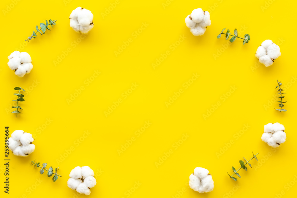 Flowers frame with fresh eucalyptus branches and cotton on yellow background top view space for text