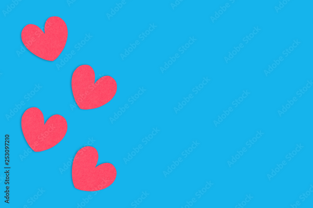 Four red paper hearts on blue table. Top view. Valentines Day concept. Copy space for your text