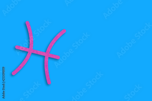 Symbol of astrological sign pisces cut out of purple paper on blue table. Top view. Horoscope concept. Copy space for your text
