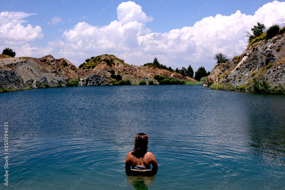 Young, beautiful woman model standing in a lake of a old sandmining place on holiday in Spain