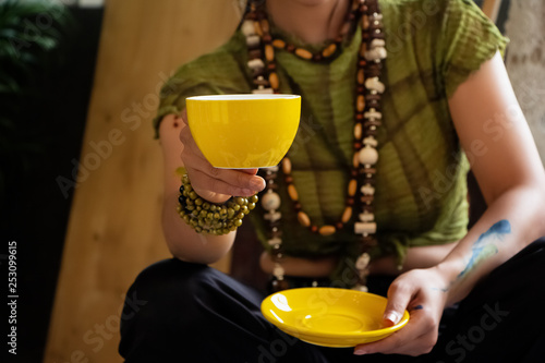 In selective focus of yellow ceramic coffee cup was holding by young artist hand,blurry light around