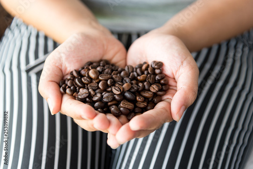 Handful of fresh organic coffee beans. coffee beans in woman hands in shape of heart. 