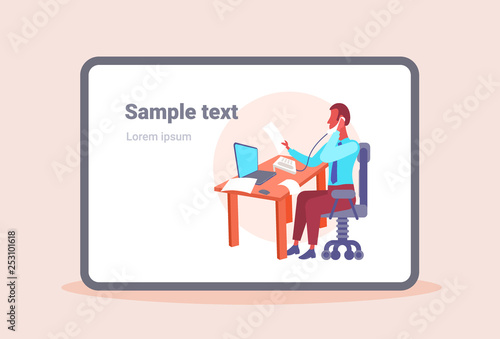 businessman sitting at desk in office looking at document while talking on phone using laptop business man hardworking process modern cabinet interior horizontal copy space