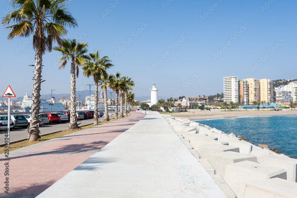 Dock of the port of Malaga with the lighthouse and the beach in the background on a sunny day