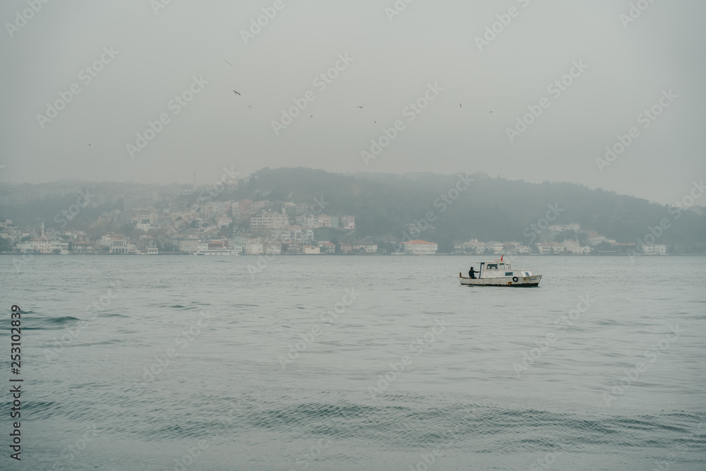 Fishing boat at Bosphorus near Ortakoy district in Istanbul, Turkey. Dramatic sky over water Fishing boat at Bosphorus near Ortakoy district in Istanbul, Turkey. Dramatic sky over water