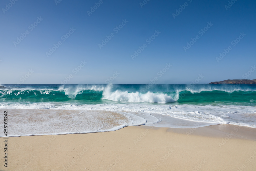 white sand of a beautiful beach and  waves of a turquoise sea under a blue sky