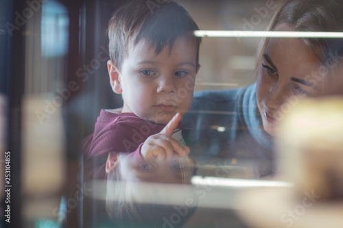 happy family, blonde mother and her beautiful and charismatic little son, the boy is having fun day in a cozy cafe. selective focus, noise effect