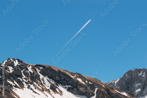 Beautiful landscape shot of snowy mountains and plane with trails