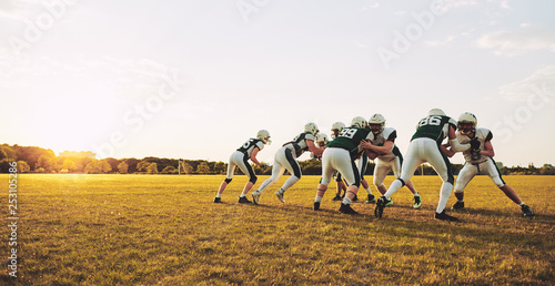 American football players doing practicing defense on a sports f