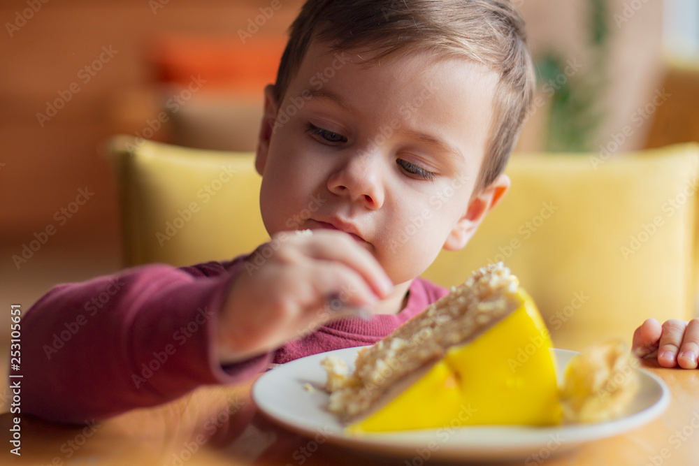 The little boy himself eats food from the fork in a cafe. Family holidays, mother and her son have a rest in the restaurant, drink cocoa and eat cake. selective focus, noise effect The little boy himself eats food from the fork in a cafe. Family holidays, mother and her son have a rest in the restaurant, drink cocoa and eat cake. selective focus, noise effect