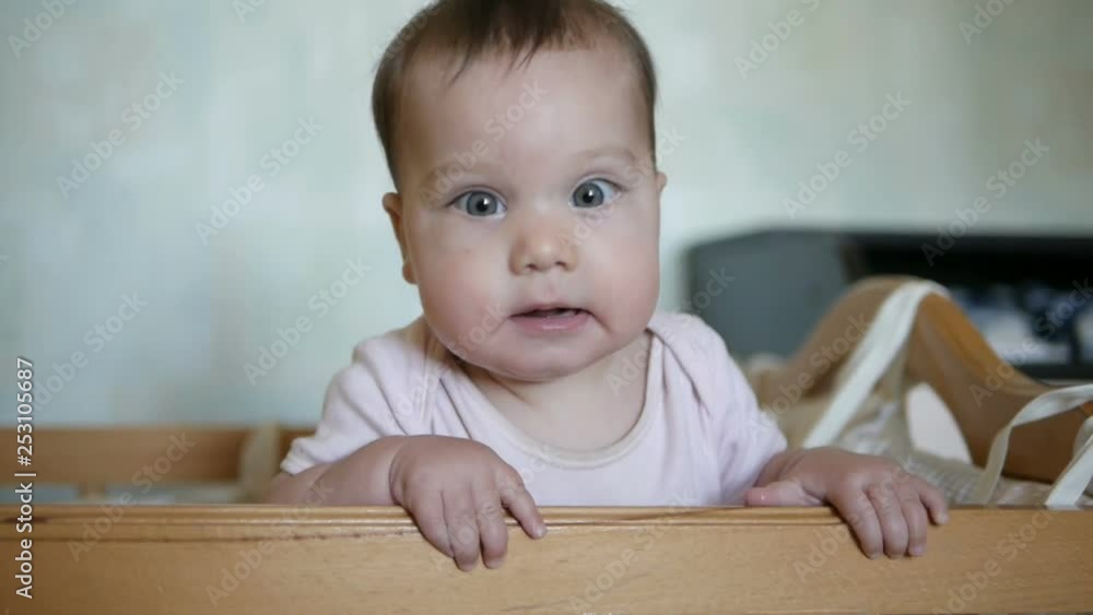 Little funny girl standing in baby bed and laughing. Happy childhood concept Little funny girl standing in baby bed and laughing. Happy childhood concept