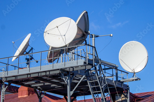 Foto Satellite dishes on the roof of the building, blue sky, parabolic antenna