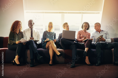 Smiling group of diverse businesspeople sitting on an office sof