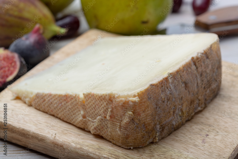 Piece of French cheese Tomme de Brebis made from sheep milk served as dessert with fresh figs and pears