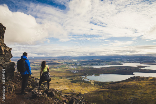 Boy in blue jacket with a girl hiking the Esja mountain near Reykjavik Iceland on a sunny afternoon