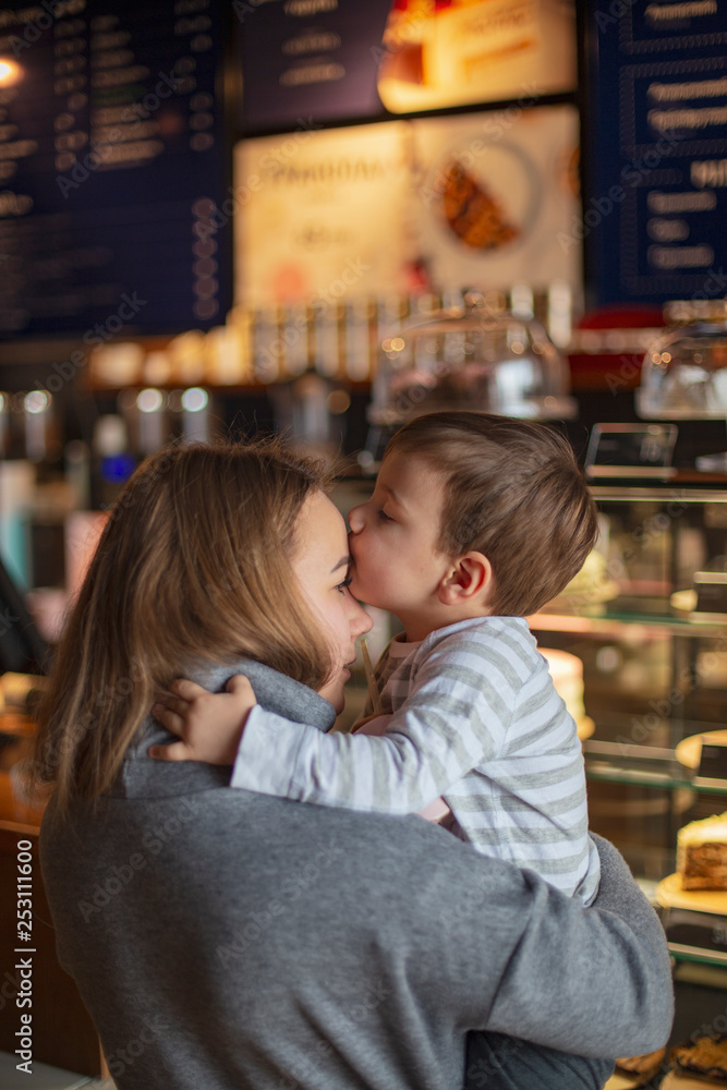happy family on vacation in a cafe. Mother and son in front confectionery display cases chosen desserts show a finger on pies and cakes. selective focus, noise effect happy family on vacation in a cafe. Mother and son in front confectionery display cases chosen desserts show a finger on pies and cakes. selective focus, noise effect