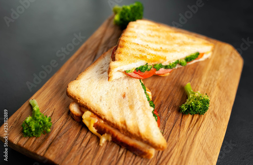 Broccoli cheese sandwiches on wooden cutting board  on concrete  slate background