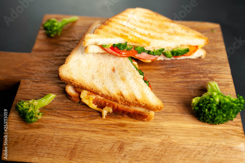 Broccoli cheese sandwiches on wooden cutting board, on concrete, slate background