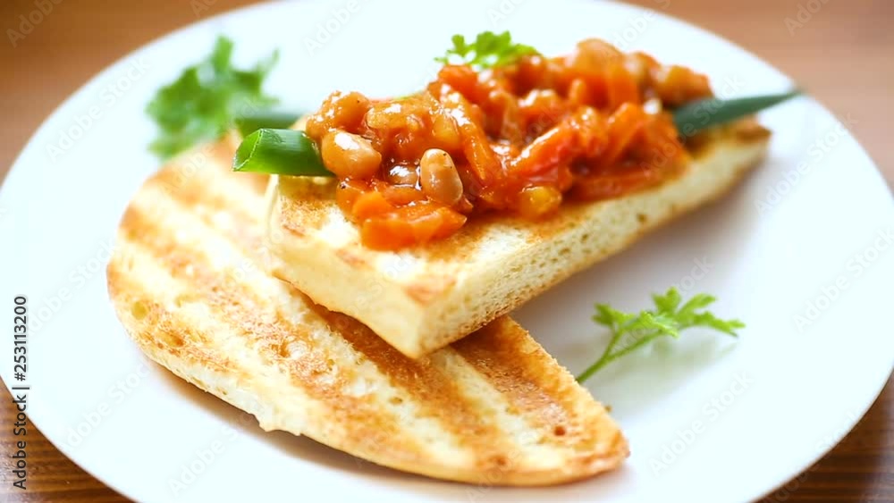 fried bread toasts with stewed beans and vegetables in a plate on a wooden table fried bread toasts with stewed beans and vegetables in a plate on a wooden table
