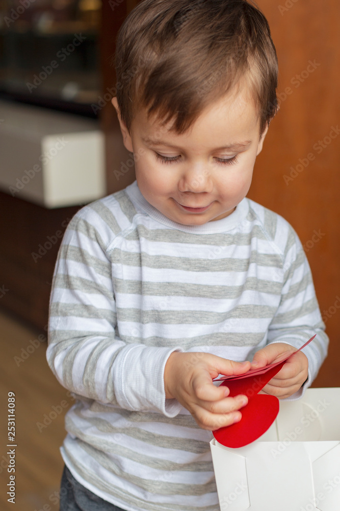 handsome little boy holding a red paper heart symbol of love for his mother. concept for the celebration of March 8 or Mother's Day. selective focus, noise effect handsome little boy holding a red paper heart symbol of love for his mother. concept for the celebration of March 8 or Mother's Day. selective focus, noise effect