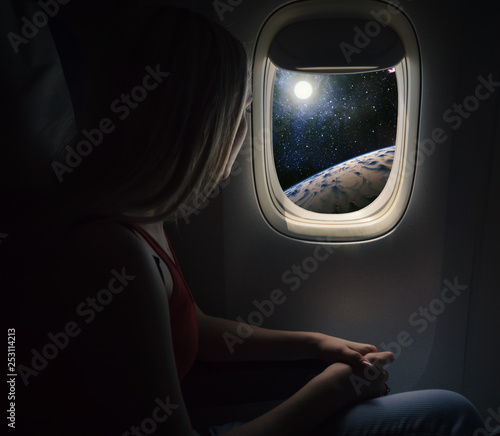 Woman in spaceship looks out the porthole. Commercial space travel concept.