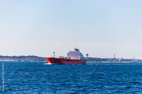 Tanker ship at sea with a refinery in the background