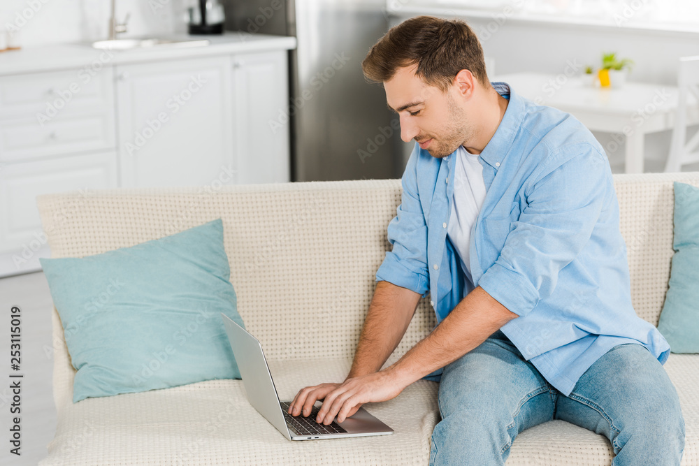 handsome man sitting on couch and using laptop at home handsome man sitting on couch and using laptop at home