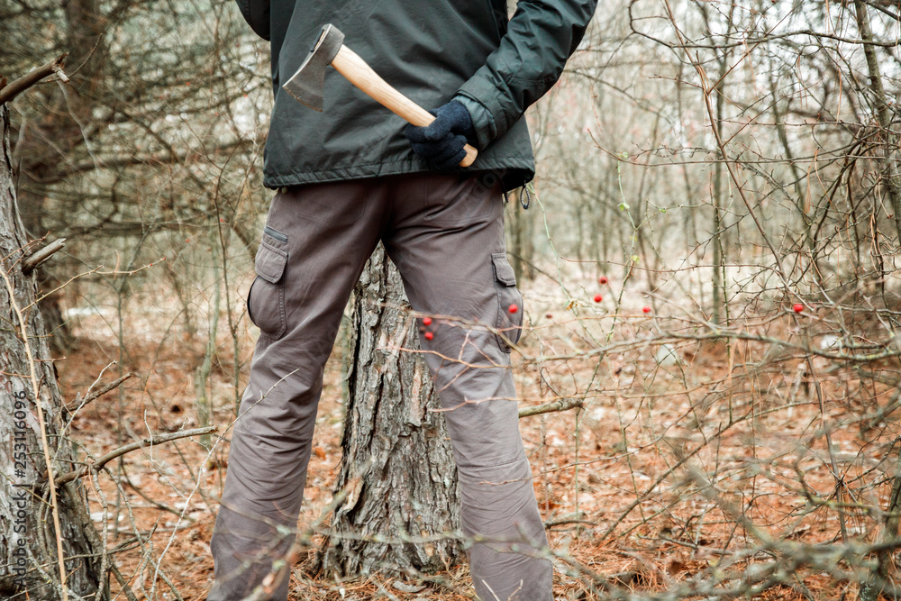 man with an axe hiding in the autumn forest and going to make criminal