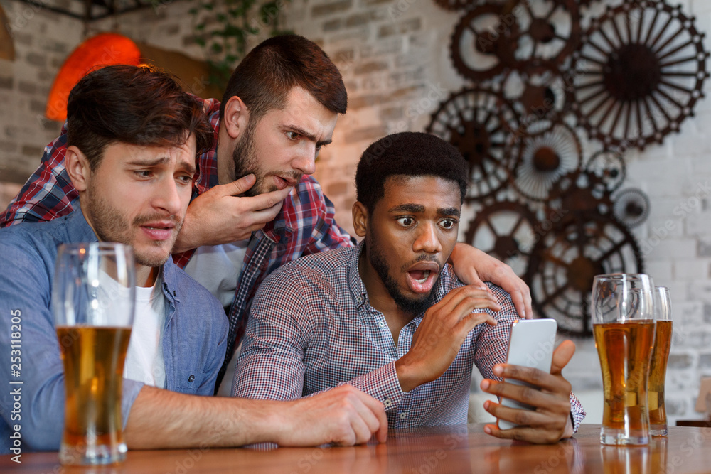 Friends watching football on smartphone in bar