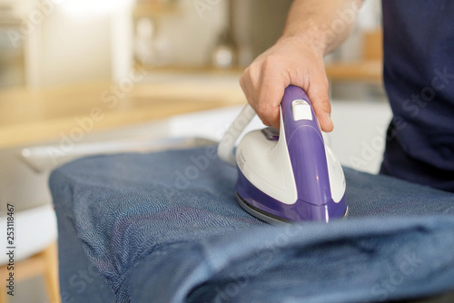 Close up of man's hands ironing shirt at home