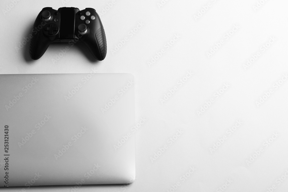 Video game controller and laptop on light background, top view with space for text Video game controller and laptop on light background, top view with space for text