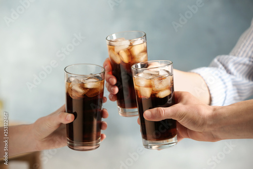 Friends with glasses of cold cola on color background, closeup photo