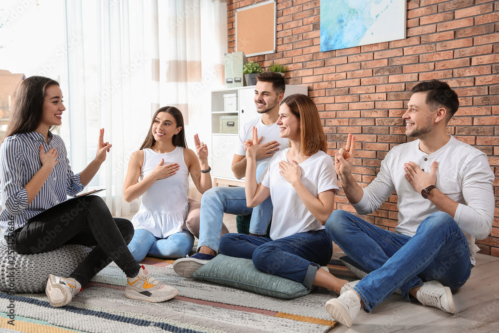 Group of young people learning sign language with teacher indoors Group of young people learning sign language with teacher indoors