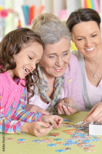 Grandmother with daughter and little granddaughter collecting puzzle