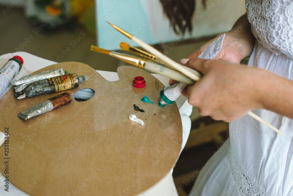 Obraz premium Artist paints picture on fabric with acrylic paints in her workshop
