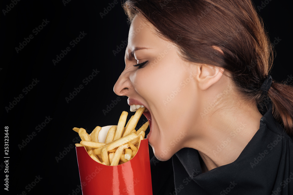 emotional woman eating tasty french fries isolated on black emotional woman eating tasty french fries isolated on black