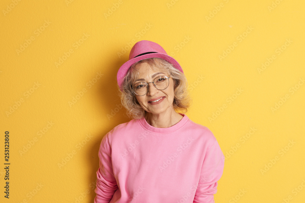 Portrait of mature woman in hipster outfit on color background Portrait of mature woman in hipster outfit on color background