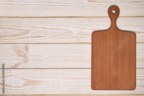 Old empty wooden cutting board on white wooden background, top view
